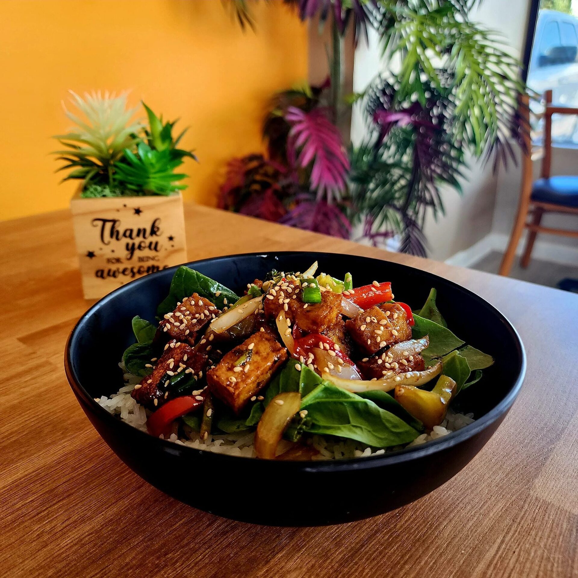 A sesame-glazed bowl over rice and spinach in the 1Chick 1Bro dining room