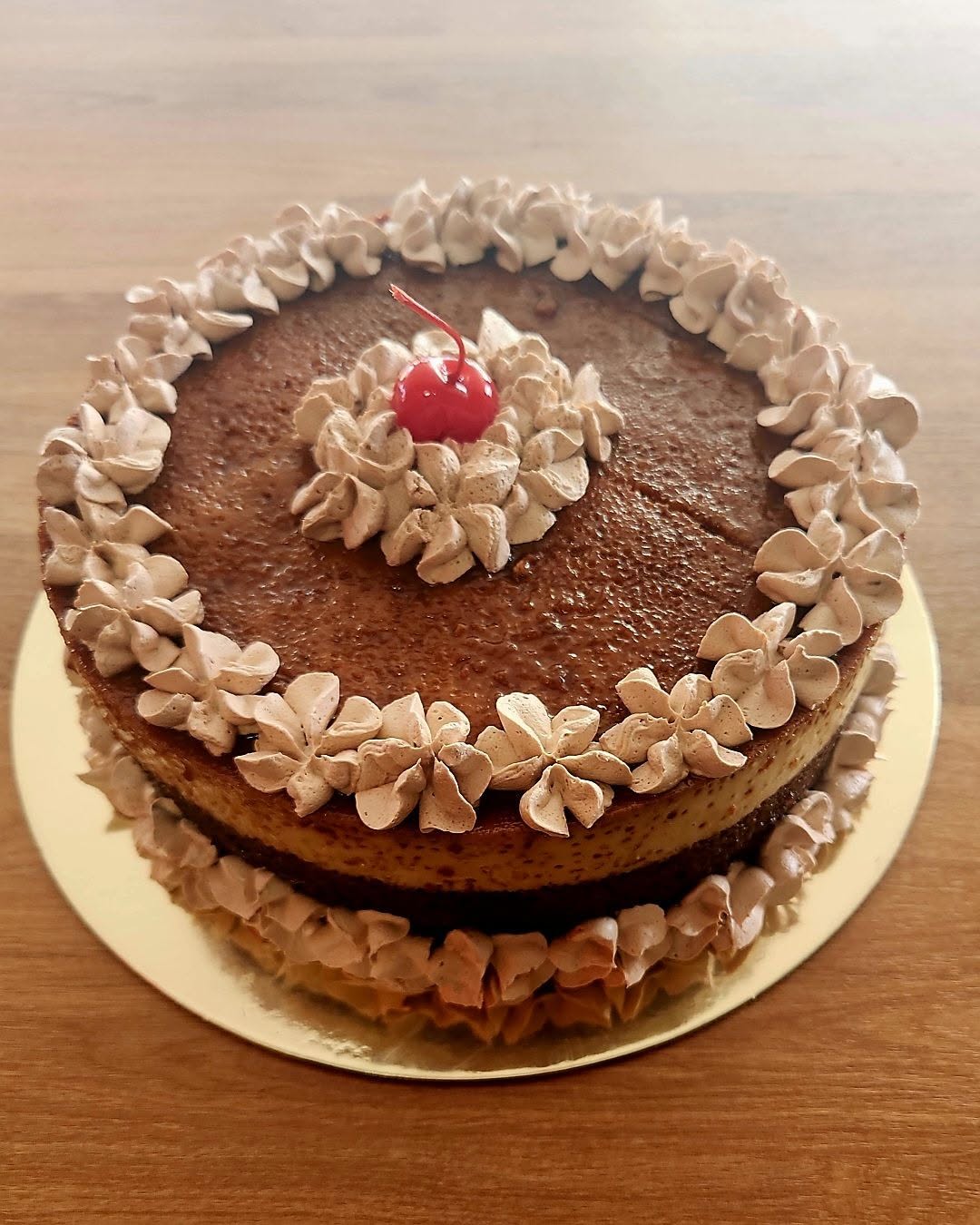 Chocolate layer cake with cream rosettes and a cherry
