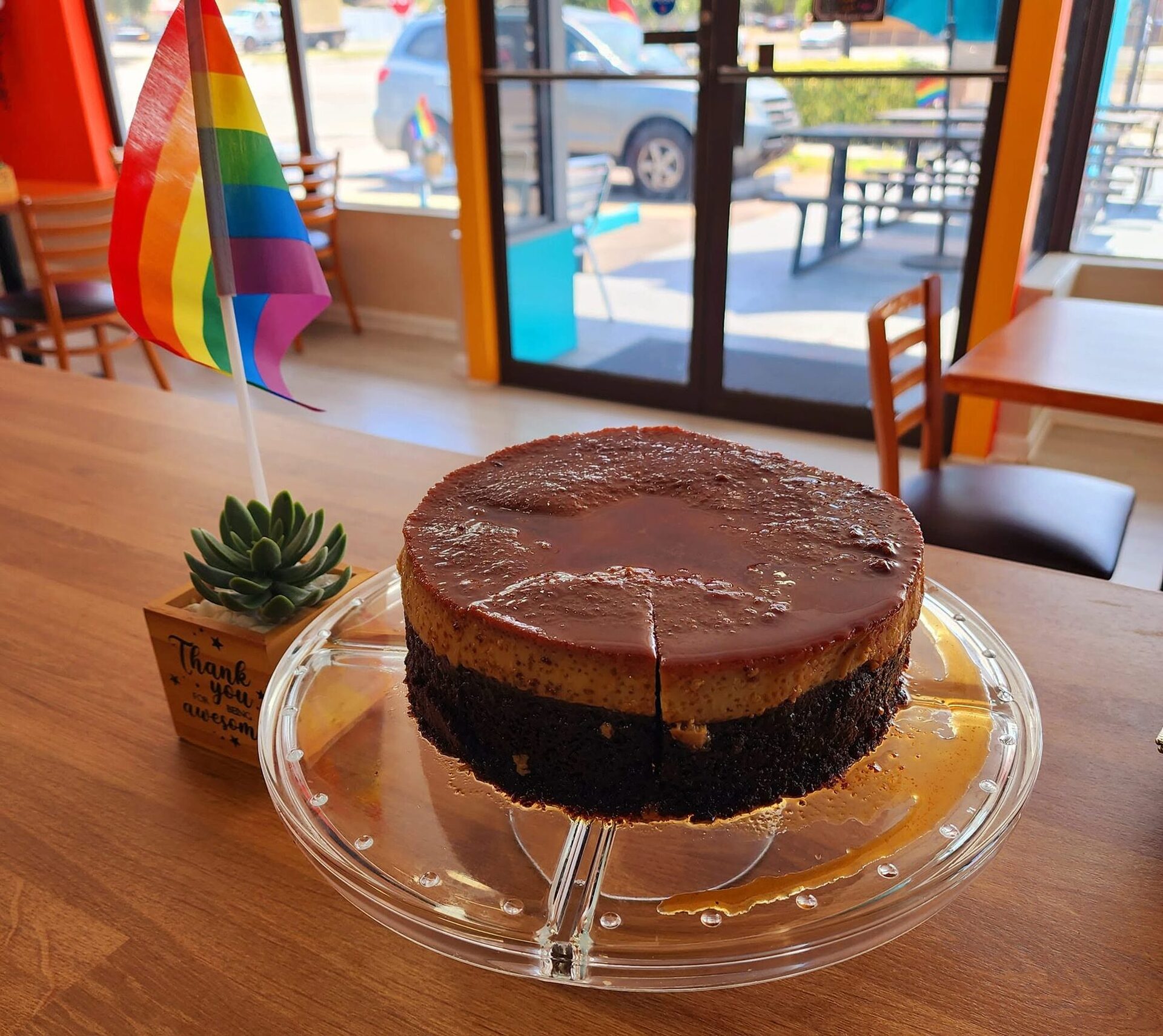 A cake in the 1Chick 1Bro window with the patio and street beyond the glass