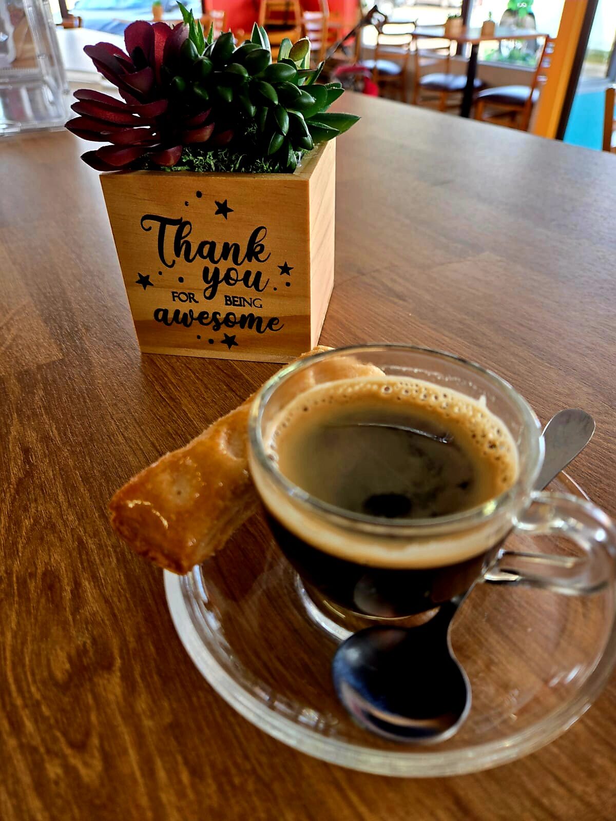 Cafecito in a glass cup beside the 1Chick 1Bro 'Thank you for being awesome' card